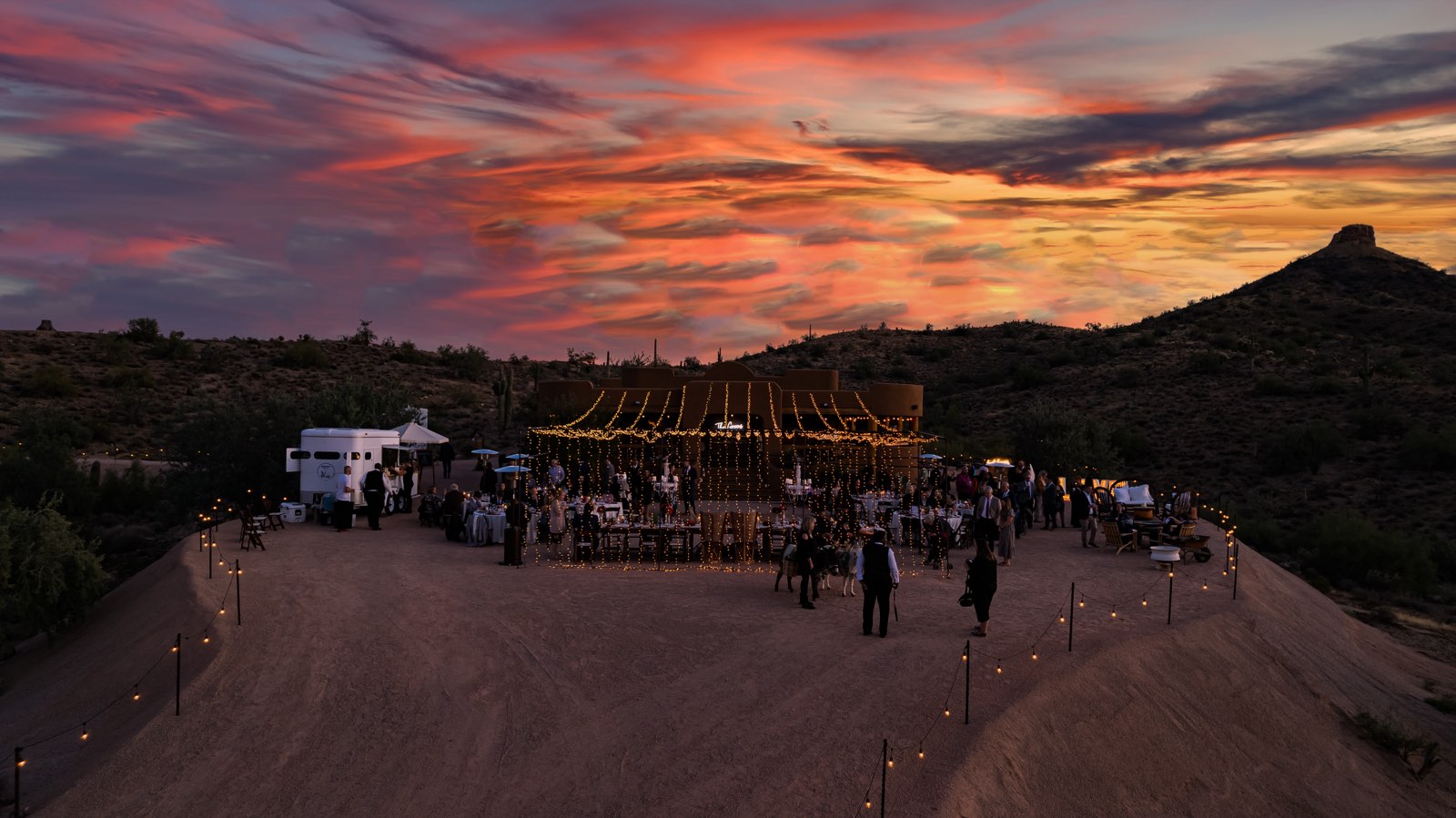 Drone photograph at golden hour: an event venue in the Queen Creek desert, strung with lights